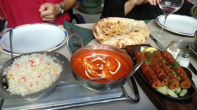 Curry de salsa de tomate con nata, arroz, pan naan y kebabs a la plancha