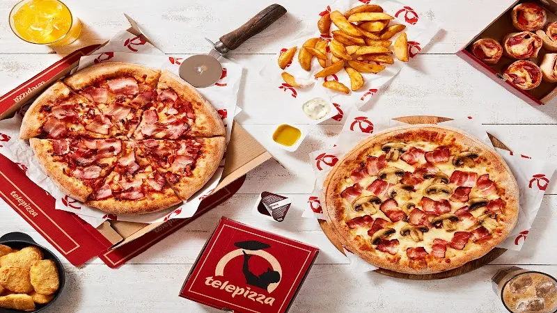 Pizza de bacon y pizza de champiñones con patatas gajo y salsas sobre cajas para llevar