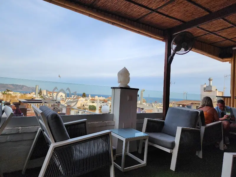 Rincón con sillones y busto de Buda frente a los tejados de Nerja y el mar