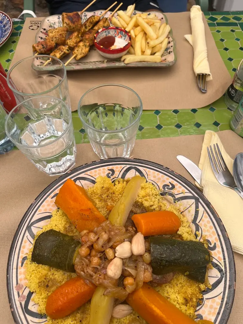 Cuscús de verduras con garbanzos y cebolla caramelizada, y brochetas de pollo con patatas