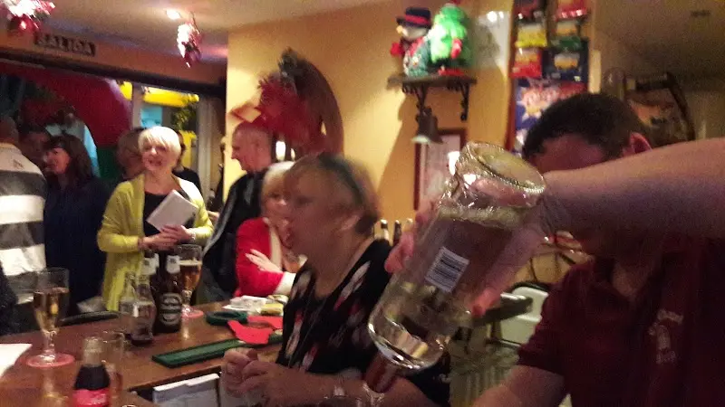 Clientes reunidos en la barra con bebidas en una noche animada