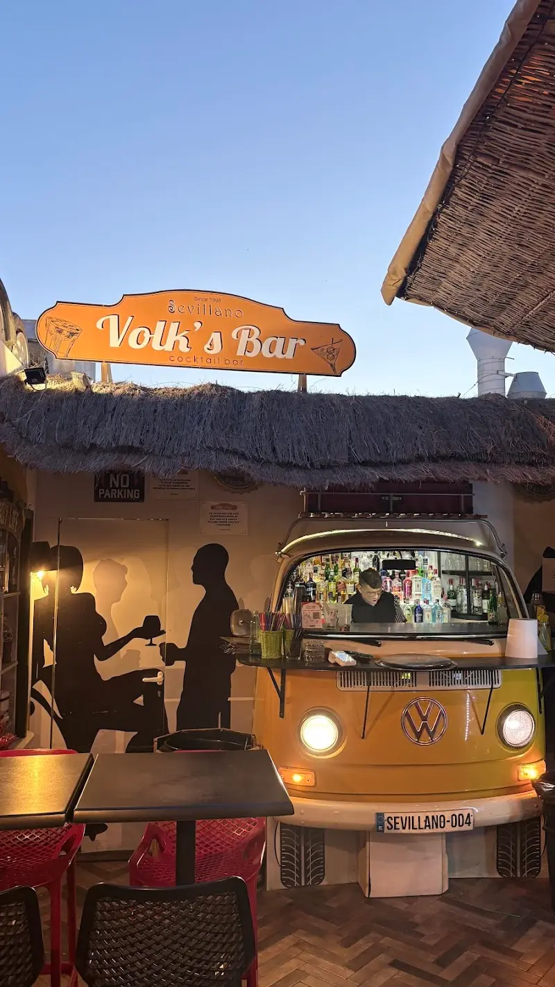 Barra de cócteles dentro de una furgoneta Volkswagen amarilla bajo el cartel de Volk's Bar