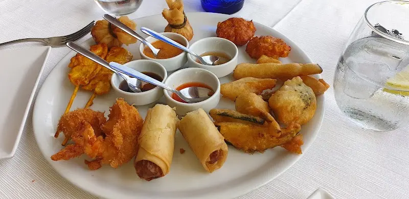 Surtido de entrantes fritos asiáticos con rollitos, tempura, brochetas y salsas