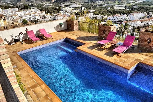 Piscina con tumbonas fucsia y vistas a las urbanizaciones y las colinas de Nerja
