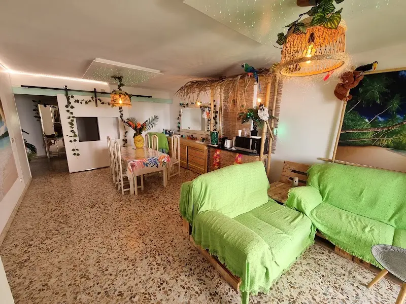 Salón de Wonder Rooms con sofás verdes, comedor y decoración tropical con lianas y loros