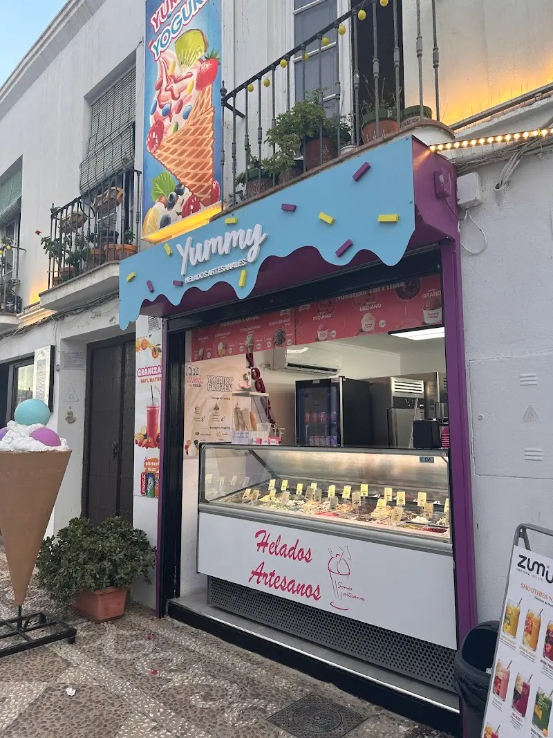 Heladería Yummy al atardecer, con luces en el balcón y vitrina de helados artesanos